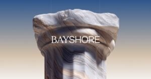 Rock column with layered, swirled patterns against a gradient sky, bearing the BAYSHORE text across the middle.
