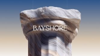 Rock column with layered, swirled patterns against a gradient sky, bearing the BAYSHORE text across the middle.